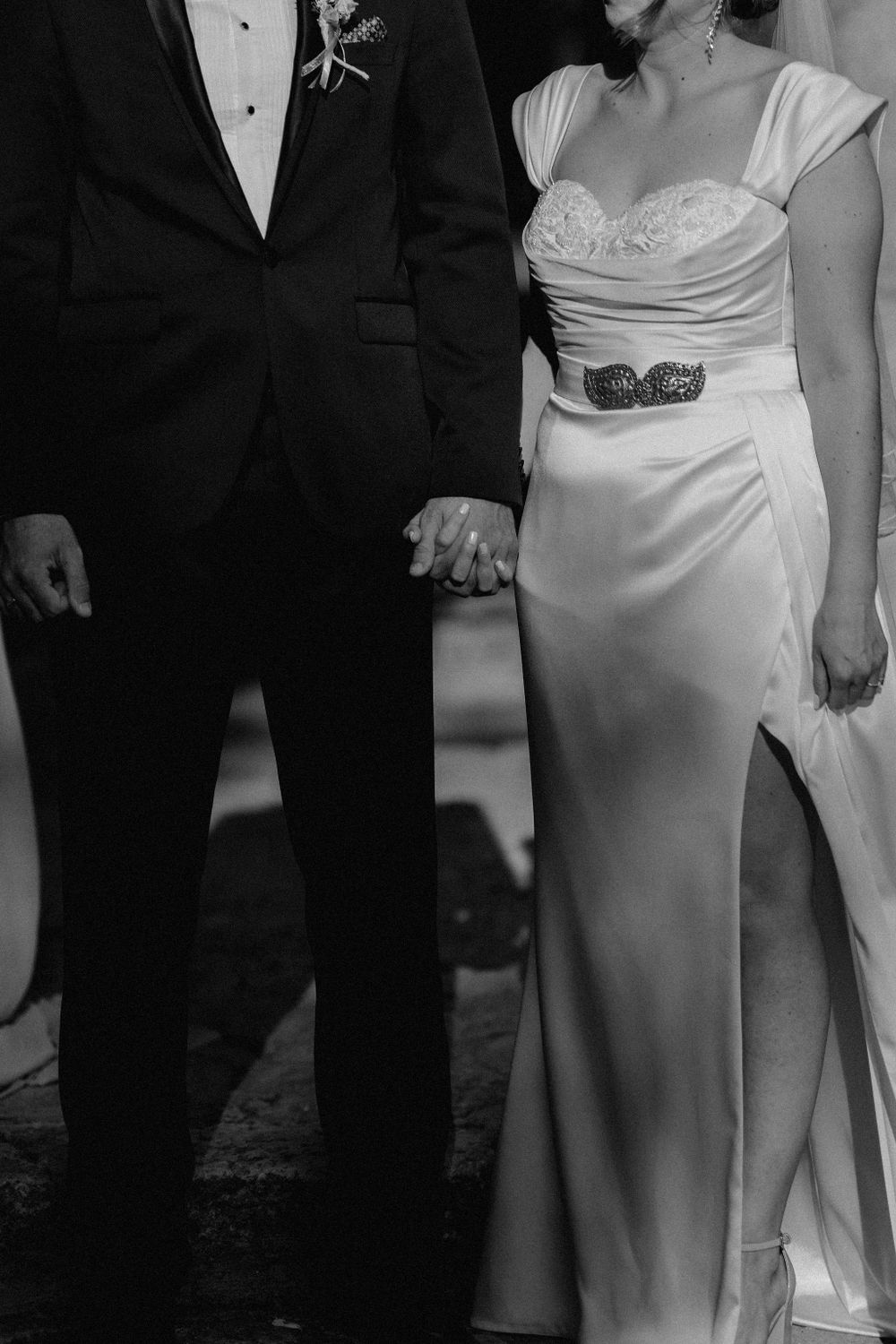 Wedding party members in formal attire standing during outdoor ceremony.