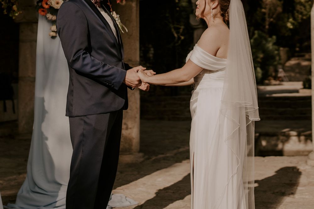 Intimate wedding ceremony moment captured under natural garden archway.
