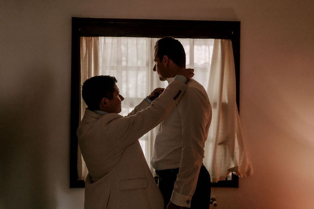 Silhouettes against window light show intimate moments of wedding preparation.