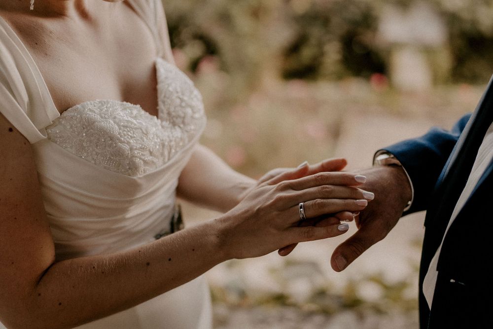 Close-up of hands exchanging wedding rings during an intimate ceremony.