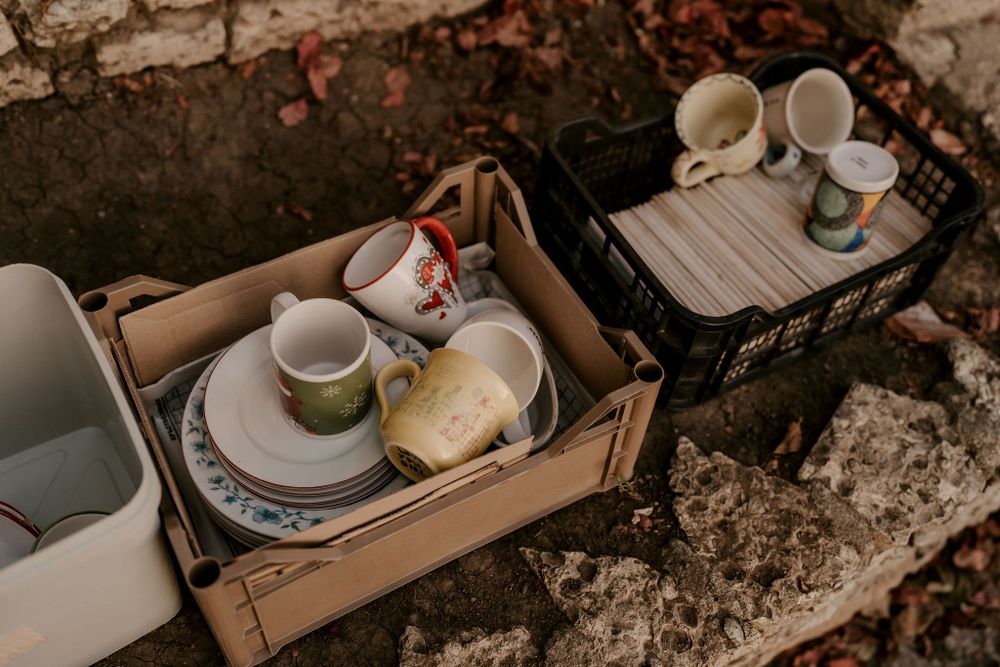 Rustic table setting with ceramic cups and plates against stone wall backdrop.