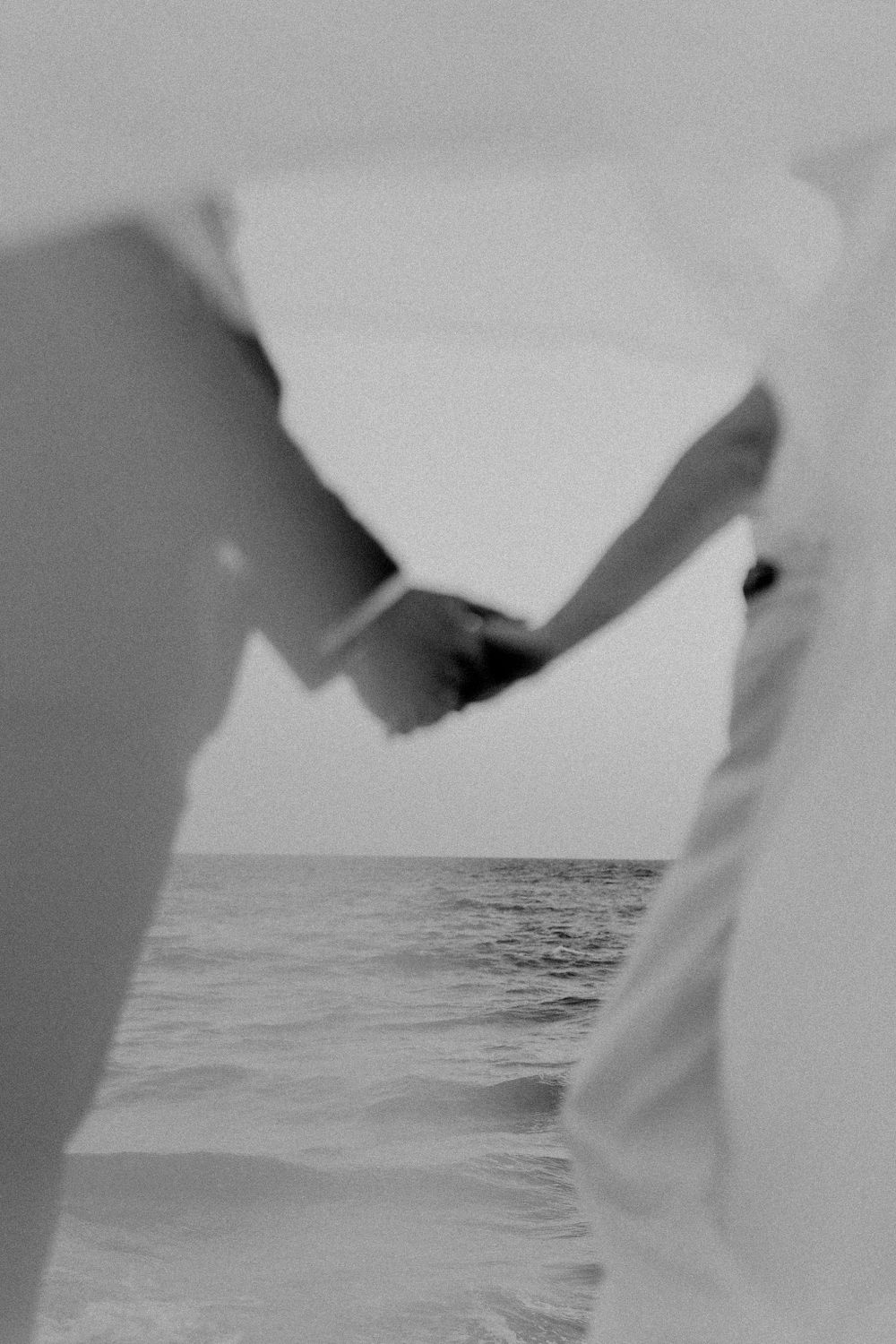 Ethereal beach scene with flowing white fabric against ocean backdrop.