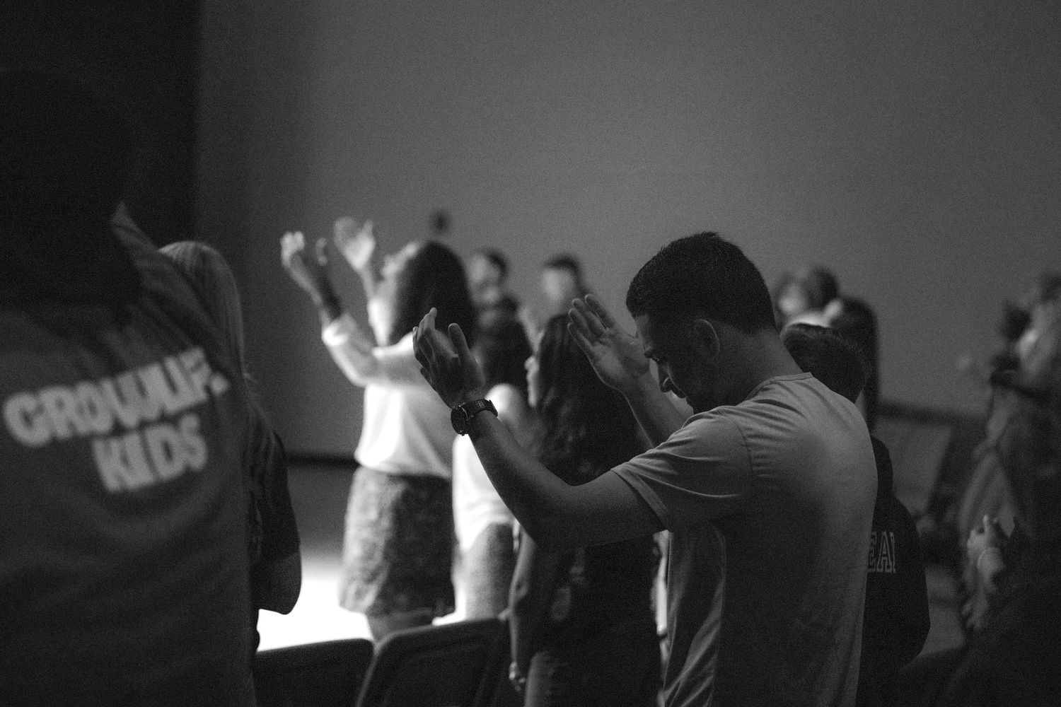 Black and white image of people raising hands during worship service.