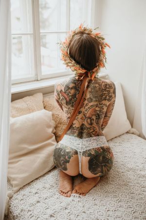 Boudoir-kuvaus studiossa, tatuoitu selkä ja pitsiset alusvaatekuvat luonnonvalossa
