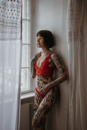 Sensuelli boudoir-kuvaus Helsingissä, nainen punaisissa alusvaatteissa ikkunavalossa