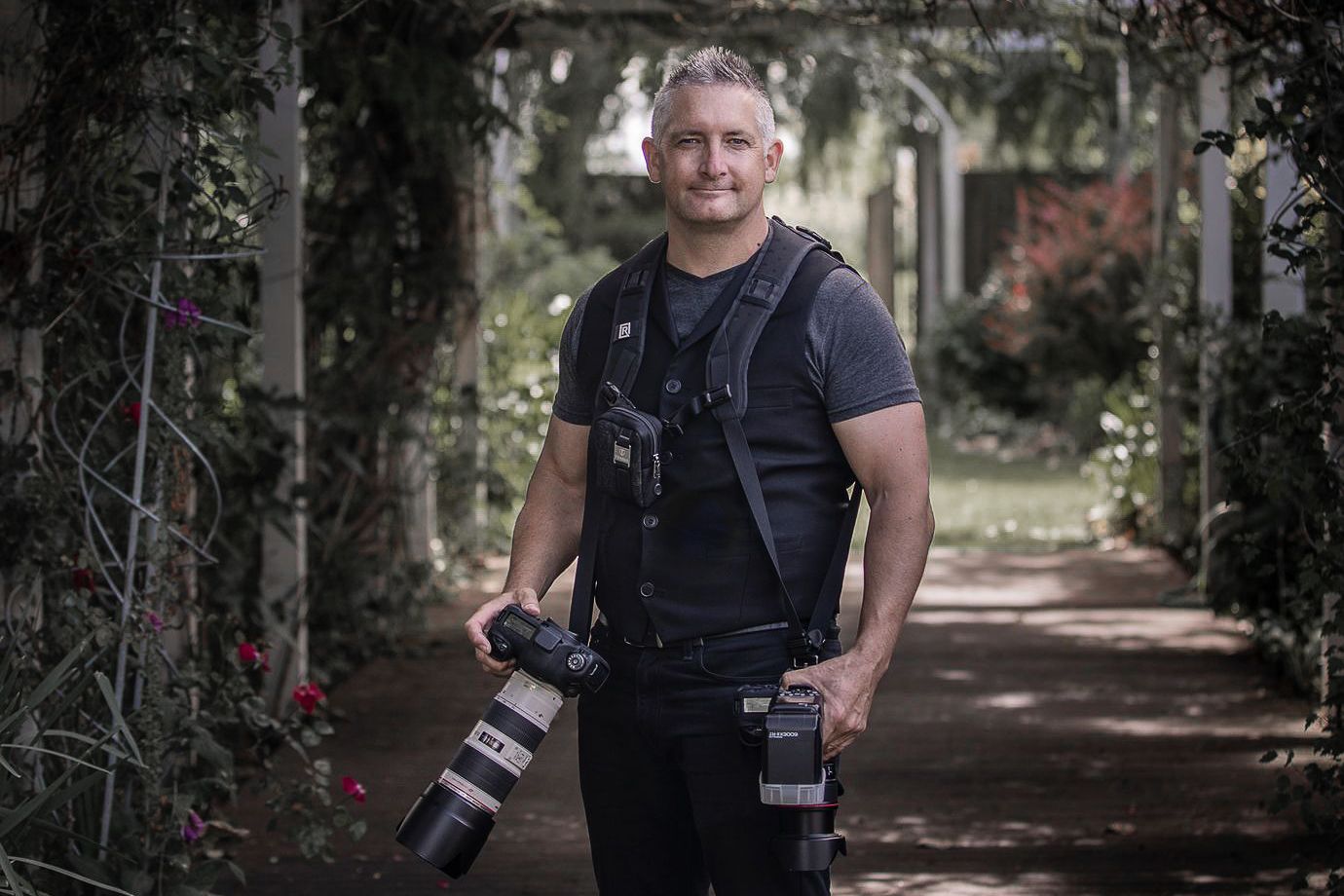 Professional photographer Brad Crocker Wedding Photographer with camera equipment standing in a garden path.