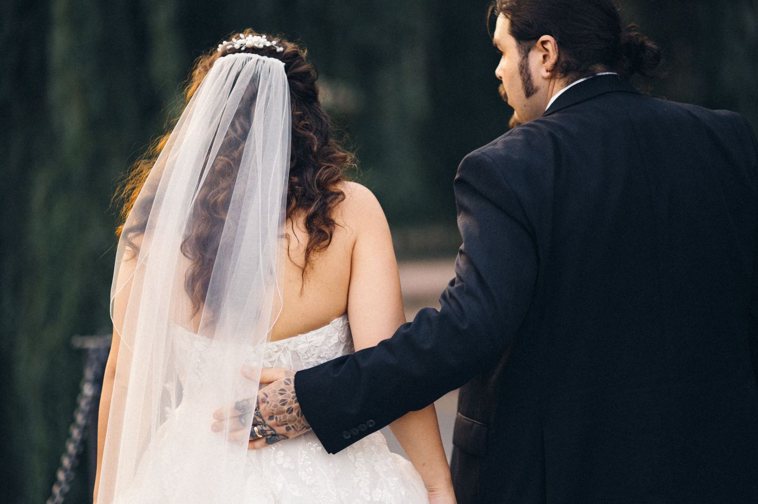 Intimate wedding moment captured from behind as couple walks together outdoors.