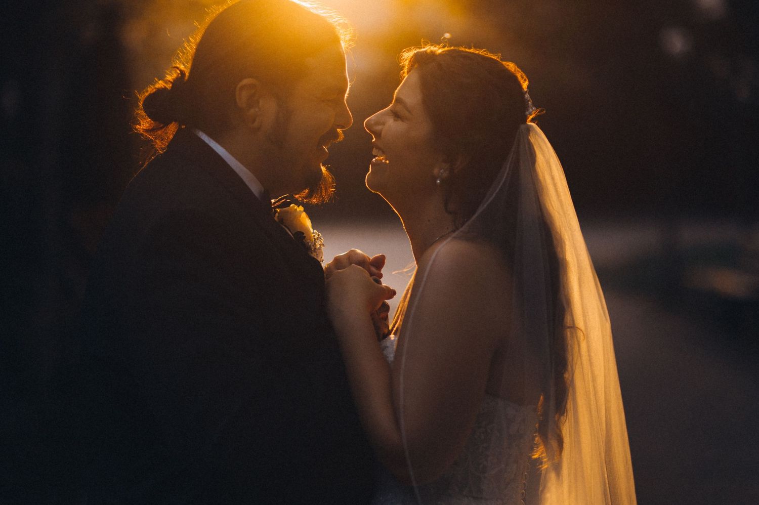 Sunset silhouette of wedding couple sharing romantic moment with golden backlighting.