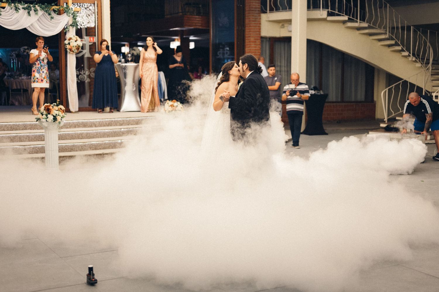 Newlyweds dancing amid low-lying fog effects during their wedding reception.