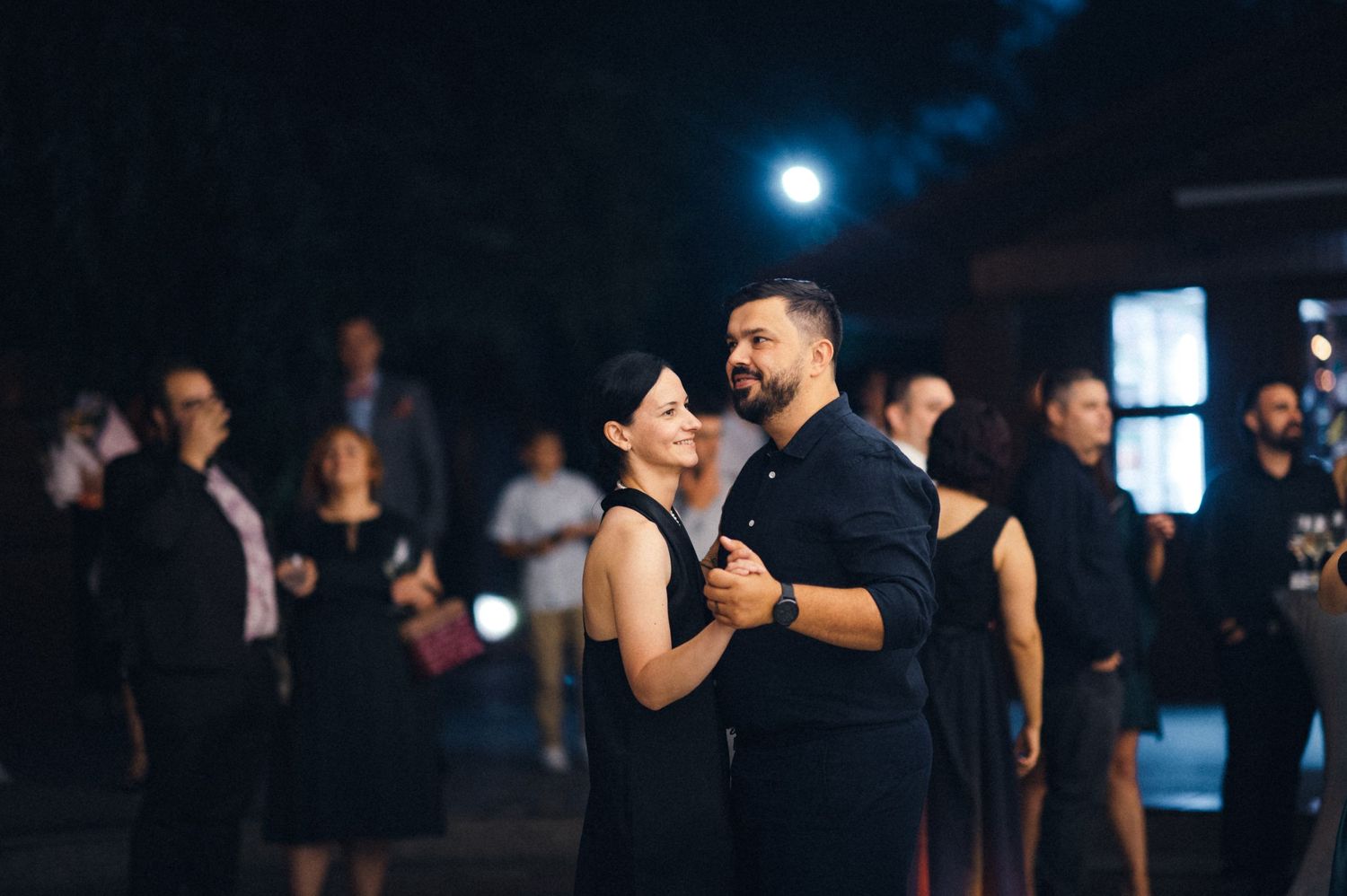 Elegant couple dancing in formal attire at a nighttime event.