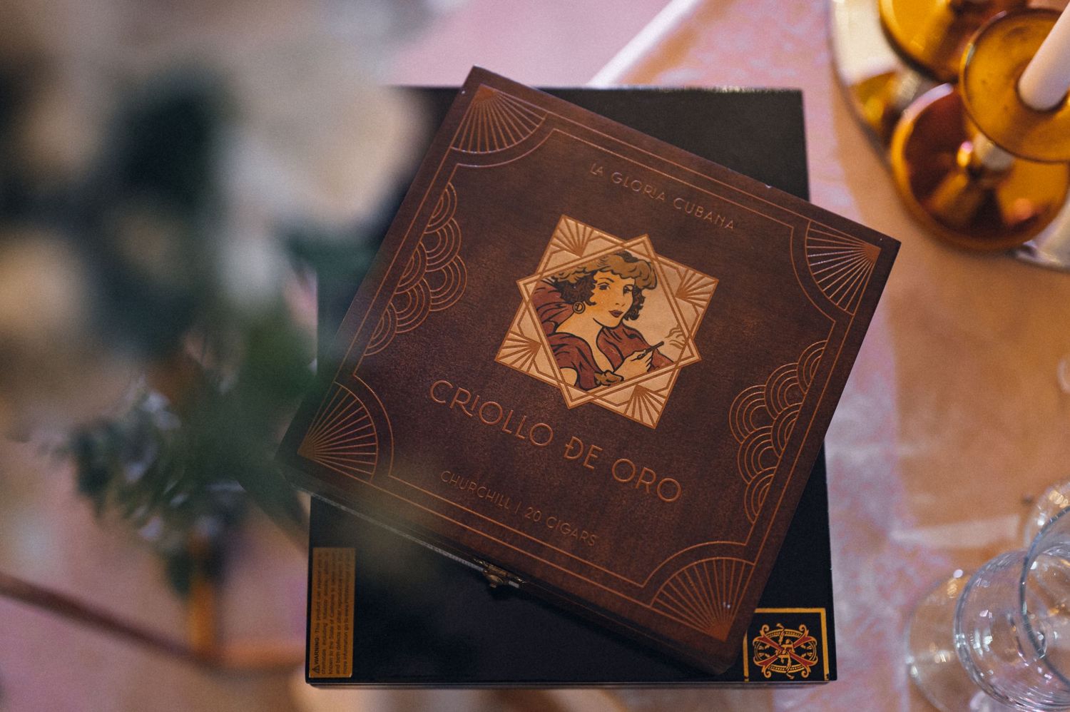 Ornate leather-bound book with decorative design on table next to drinks.