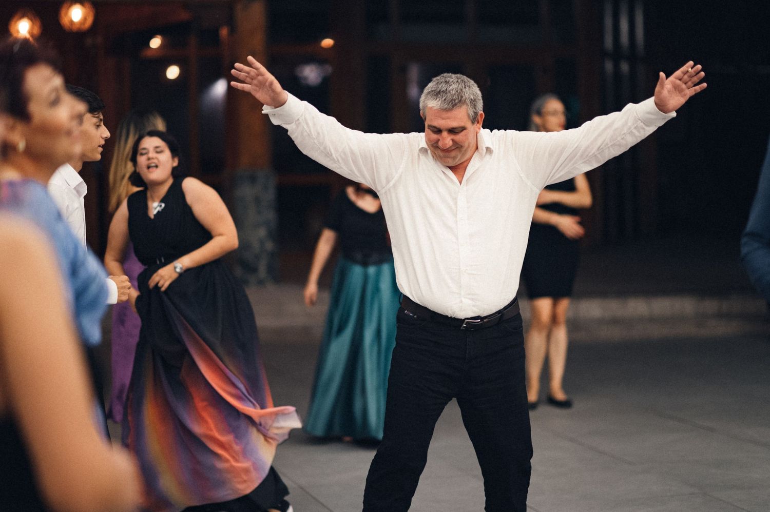 A guest dances enthusiastically with arms raised during a wedding reception celebration.