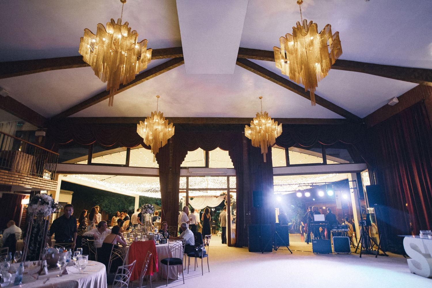 Elegant reception venue with golden chandeliers and vaulted ceiling.