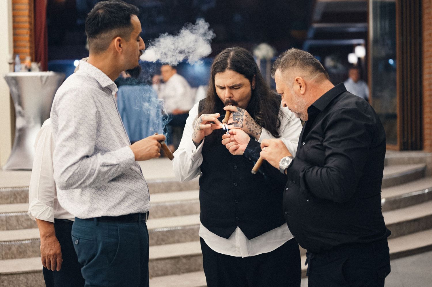 Three people standing together outdoors while smoking and having a conversation.
