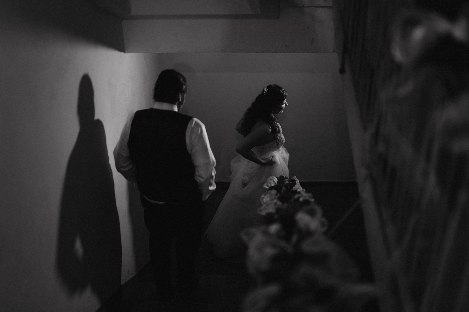 Dramatic black and white silhouette of wedding couple walking down a hallway.