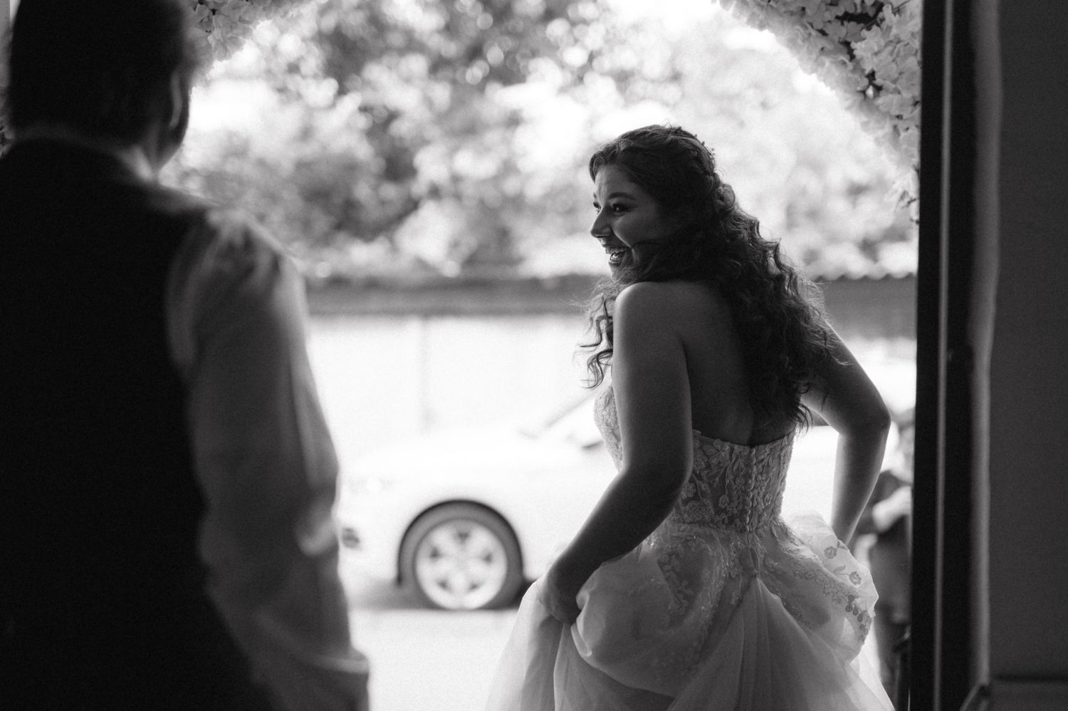 Black and white photo capturing a romantic wedding moment in a doorway.