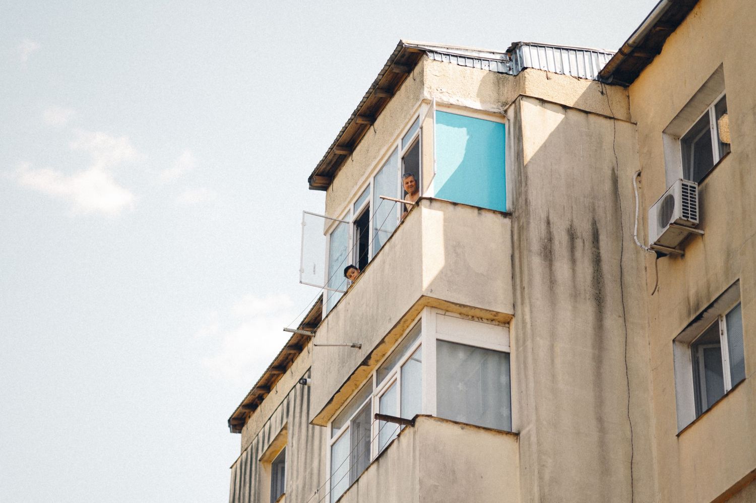 An urban apartment building facade with a bright turquoise banner hanging from a balcony.