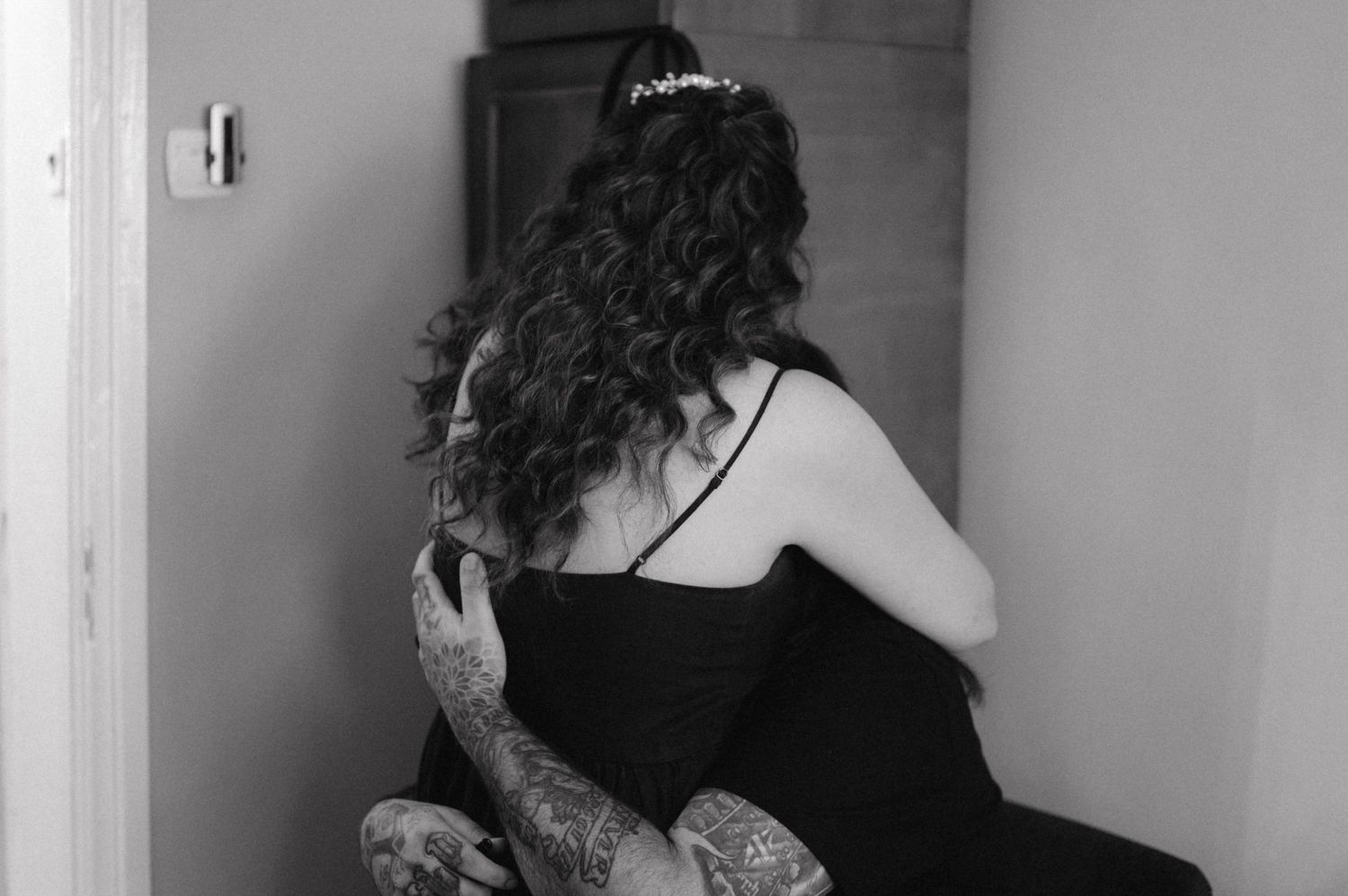 Black and white portrait of someone with long curly hair wearing a formal black dress.