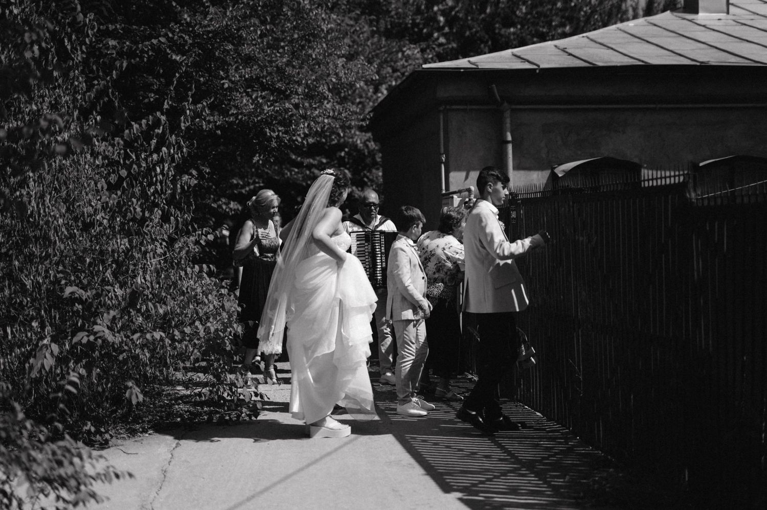 Black and white photo of wedding guests walking along an outdoor pathway.