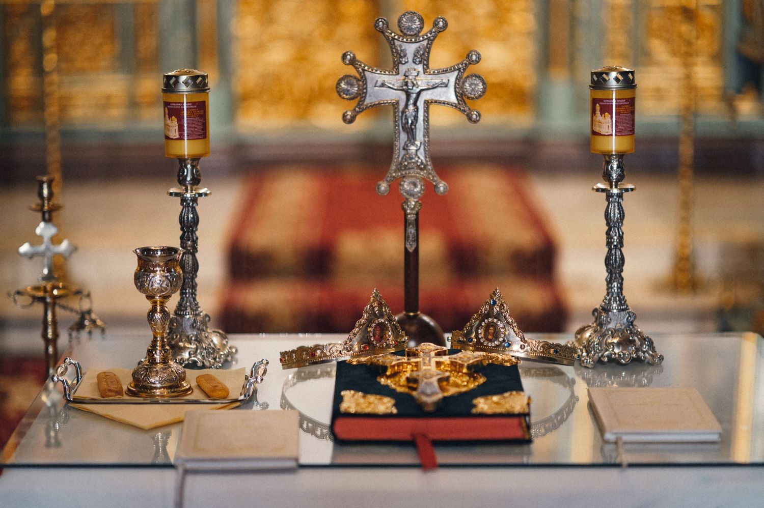 Religious altar display with ornate crosses and candles on white tablecloth.