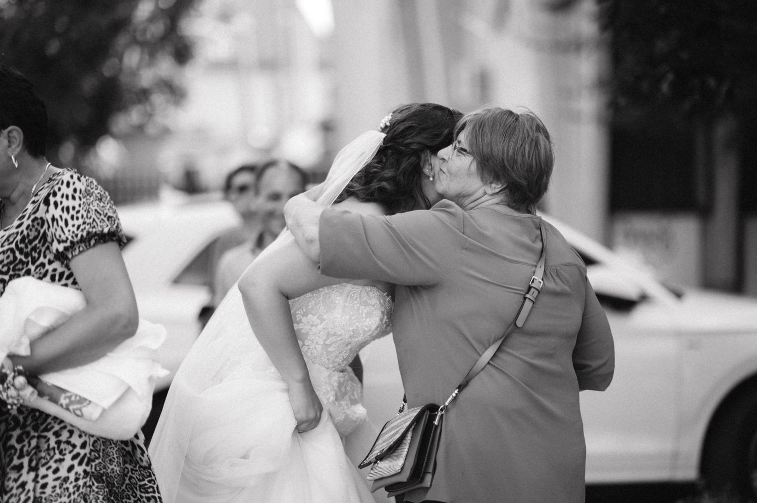 Emotional embrace during wedding celebration on city street.
