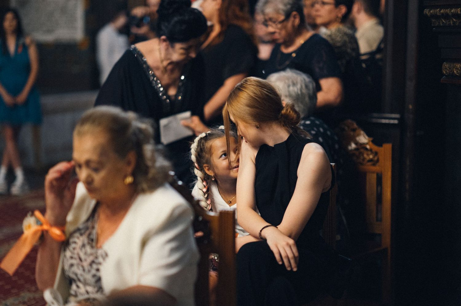 People seated in formal attire during a church ceremony.
