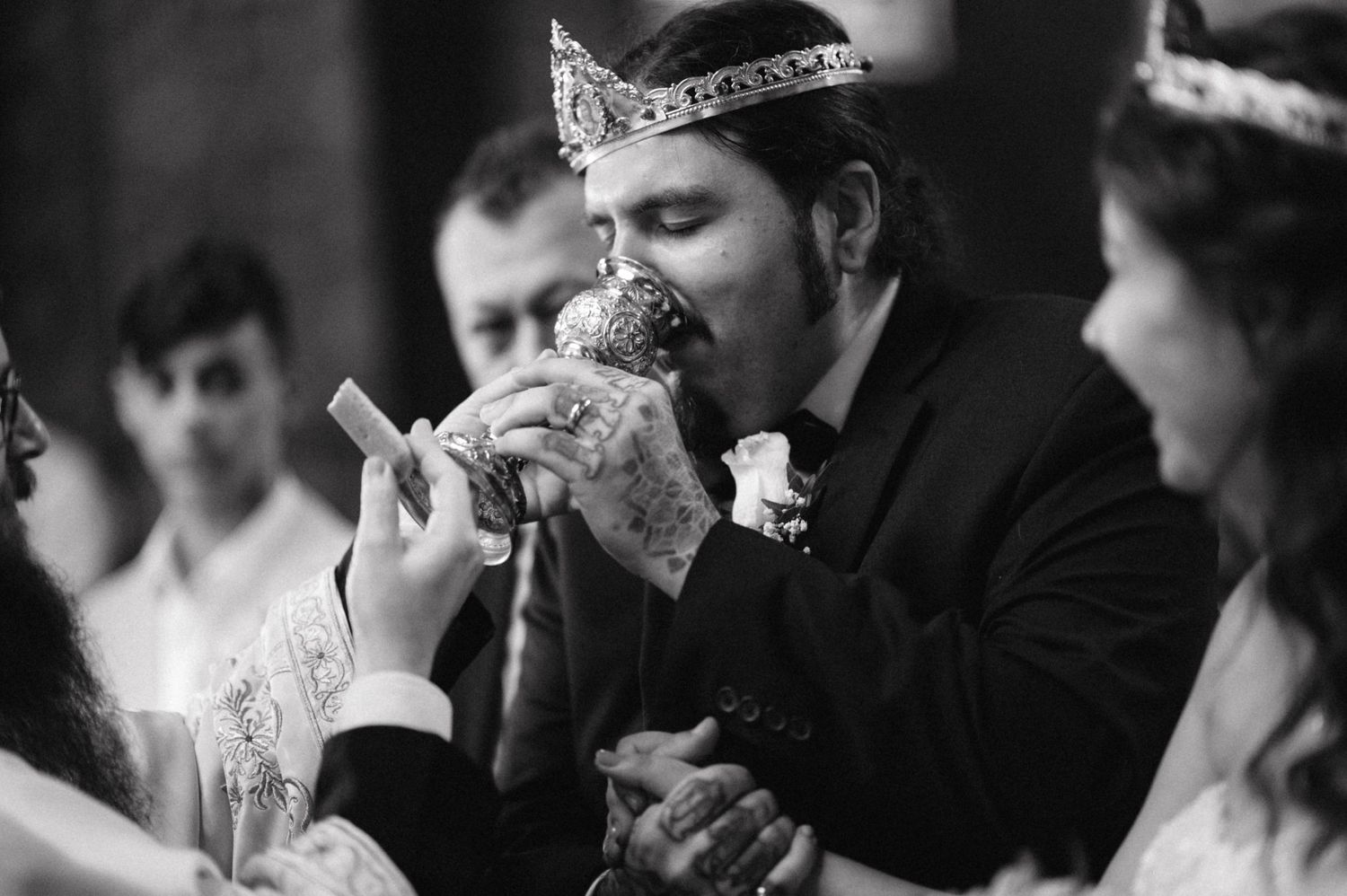 A close-up black and white photo of a wedding ceremony ritual involving a chalice.