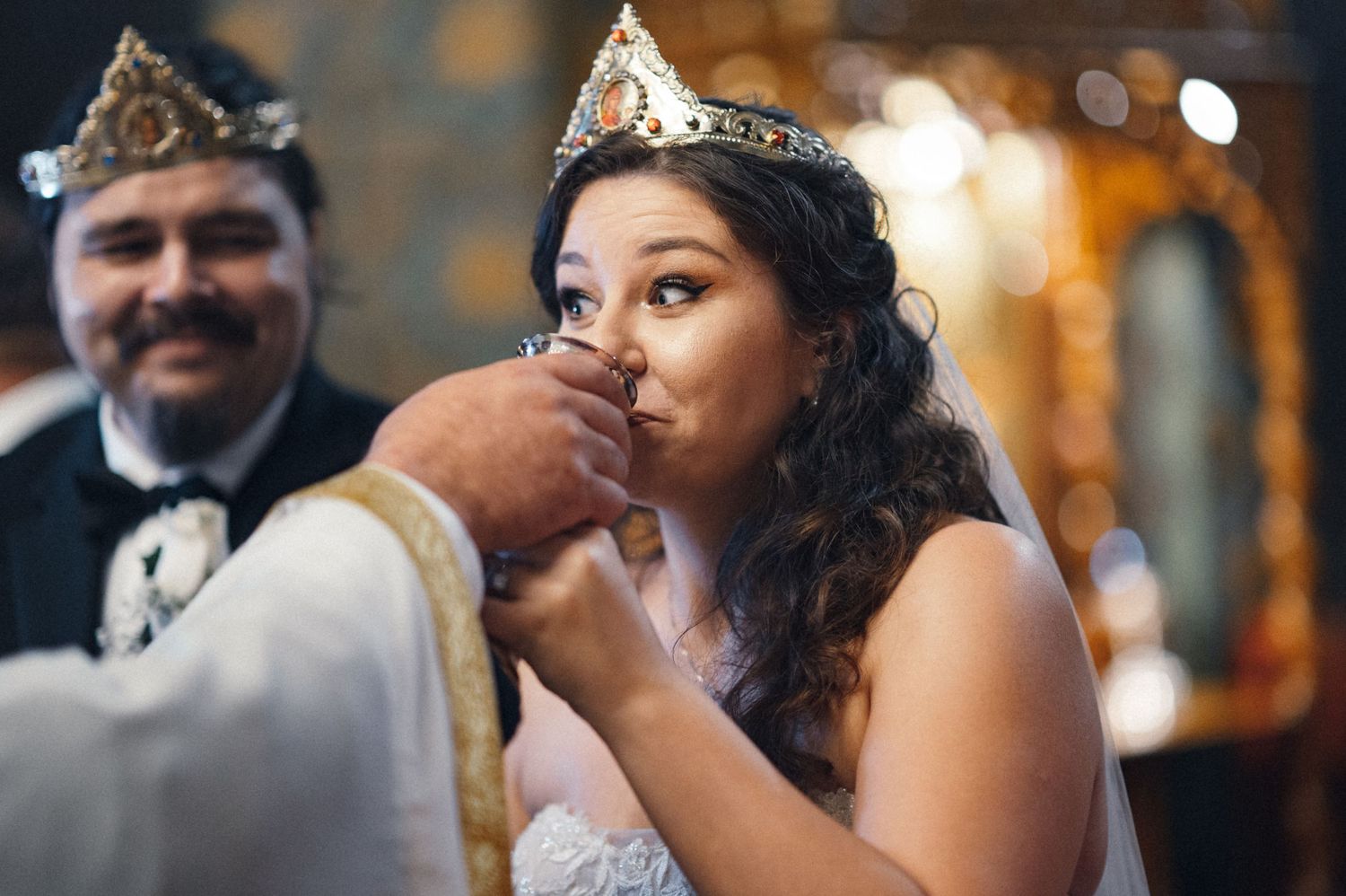 A bride participates in a traditional Orthodox communion ritual during her wedding ceremony.