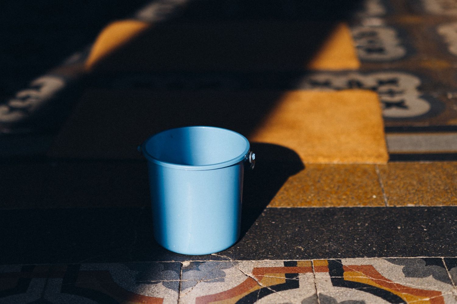 Blue metallic cup sitting on a patterned surface in dramatic lighting.