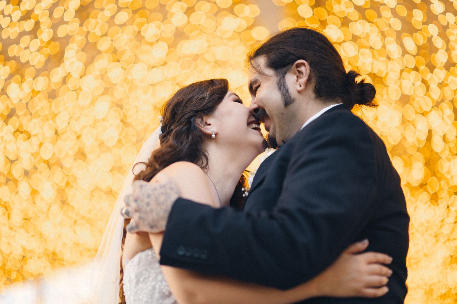 Couple sharing an intimate moment against a backdrop of golden bokeh lights.