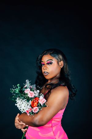 Studio fashion shot with model posing with mixed rose bouquet in vibrant pink dress.