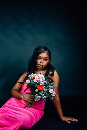 Fashion portrait in hot pink dress with mixed floral bouquet against moody teal backdrop.