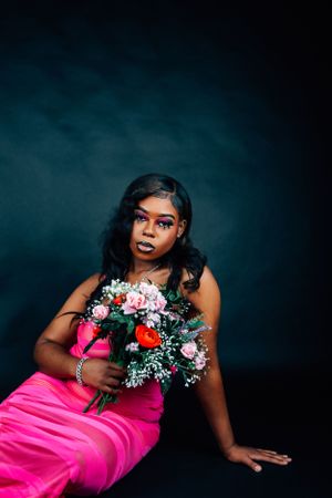 Elegant fashion photo with dramatic lighting and colorful bouquet against dark background.