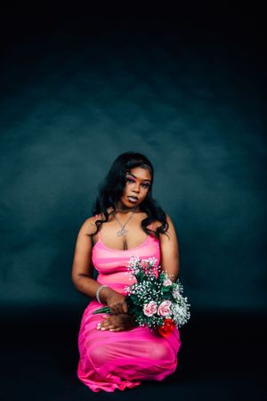 Fashion portrait featuring pink formal wear and mixed flower bouquet in studio setting.