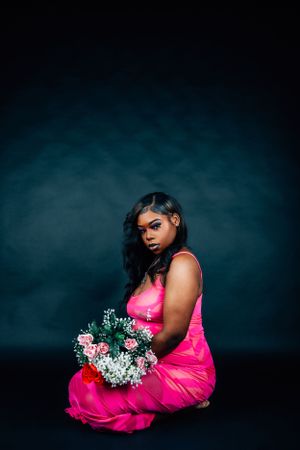 Elegant studio portrait with dramatic pose and florals against moody background.