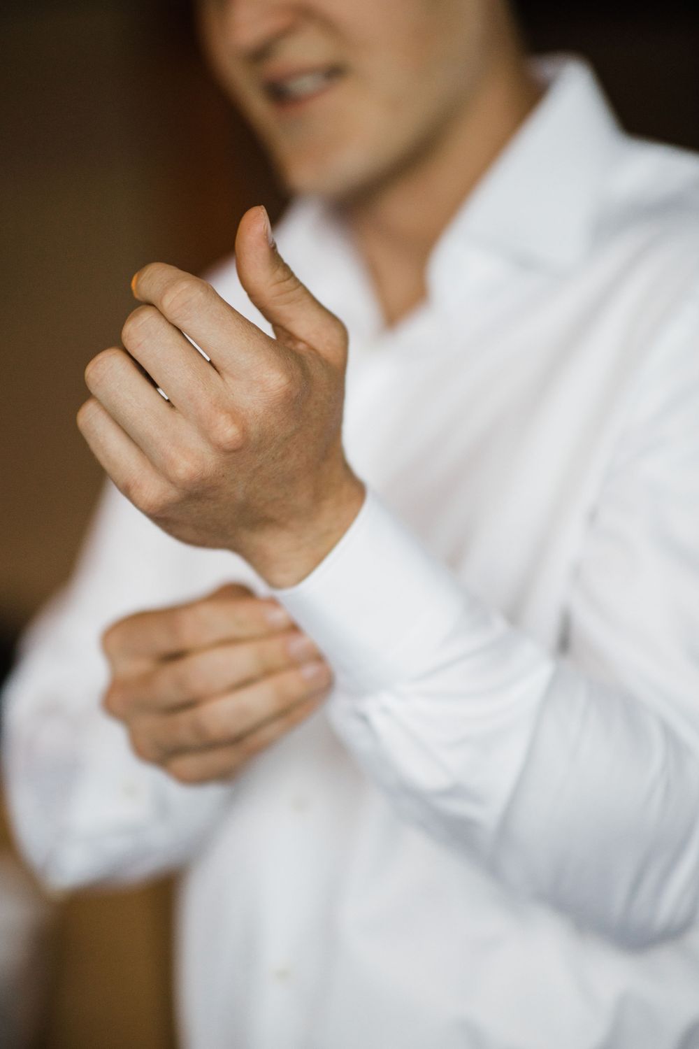 Close-up of hands adjusting white shirt cuff button.