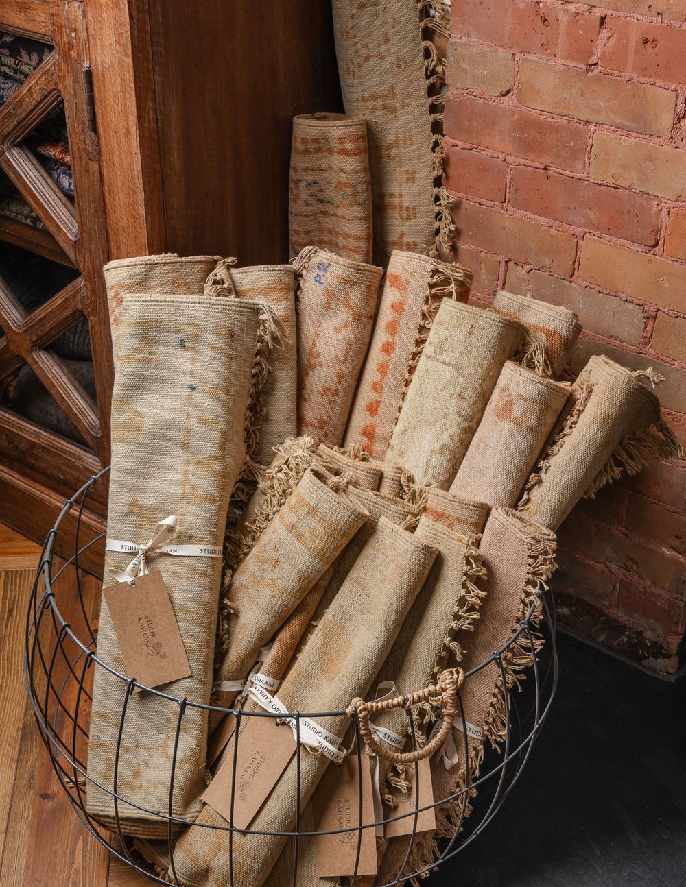 Vintage scrolls and documents displayed in a wire basket against exposed brick wall.