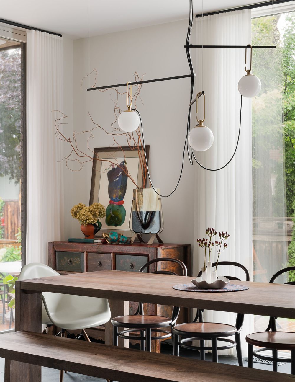 Modern dining area with unique branching pendant lights and mixed seating including bench and chairs.