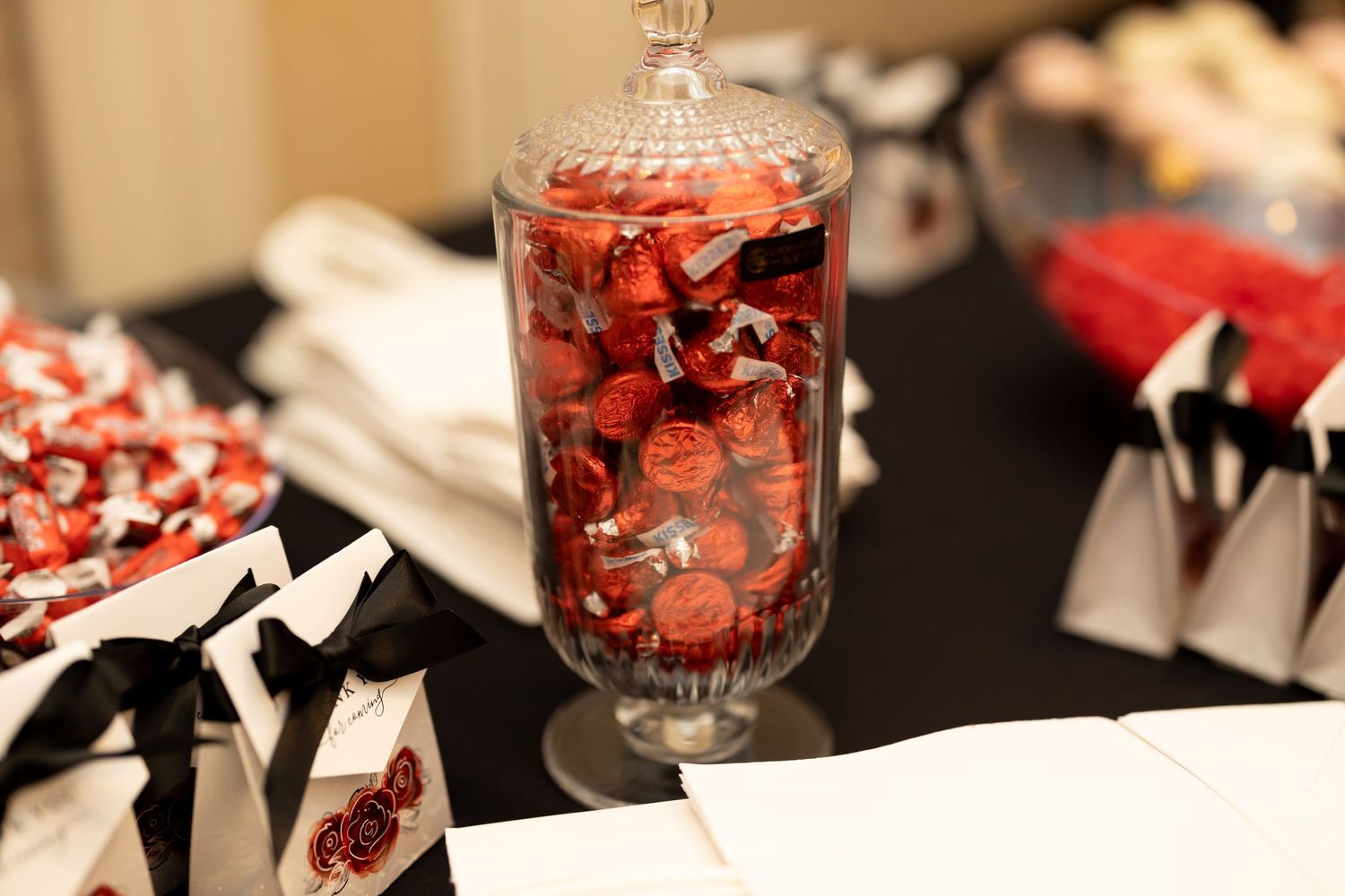 Glass jar filled with red and black candies on a decorated table setting.