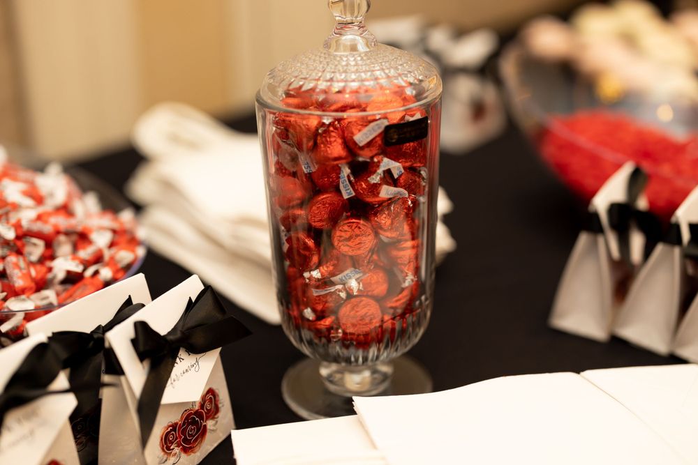Glass jar filled with red and black candies on a decorated table setting.