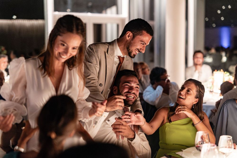 A group of friends share joyful laughter while dining together at an upscale restaurant in the evening at Forte da Crismina, Cascais