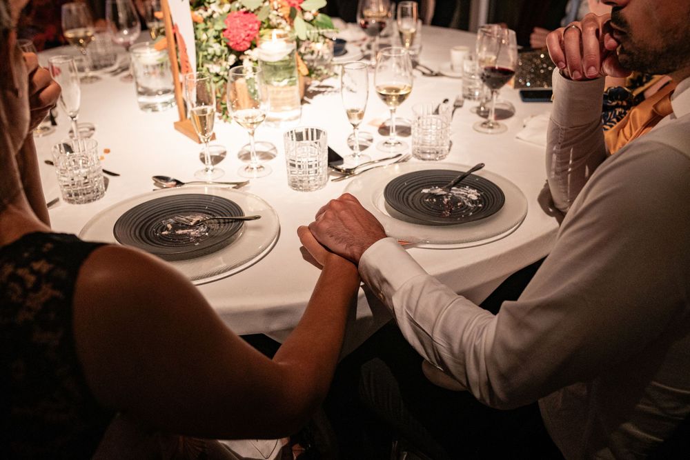 Close-up view of arm wrestling at an elegant dinner table with formal place settings and wine glasses at Forte da Crismina, Cascais