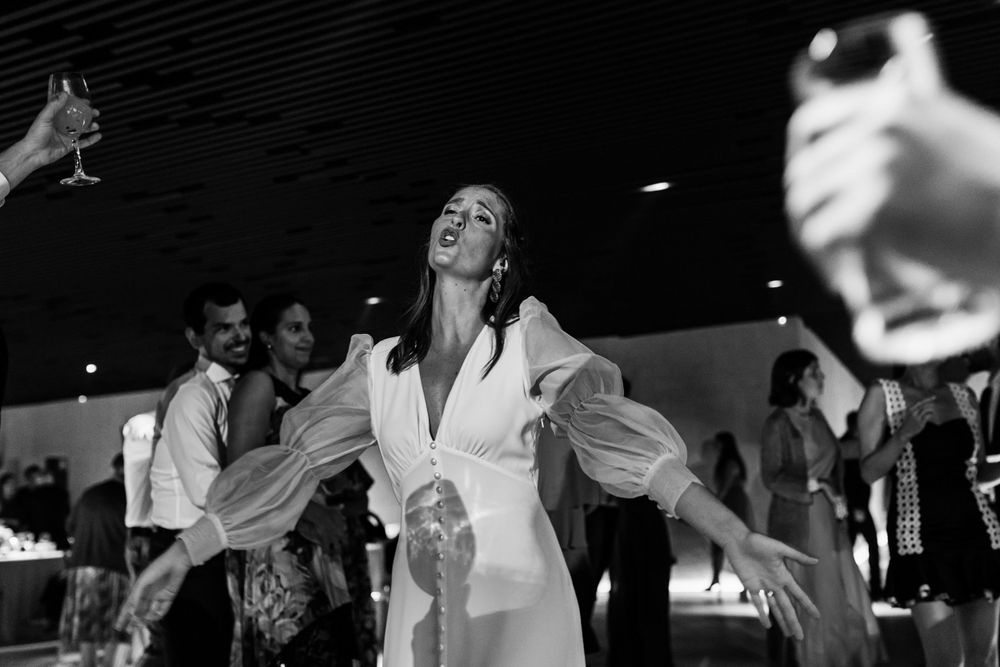 A person wearing an elegant white dress dances joyfully at a lively indoor celebration.