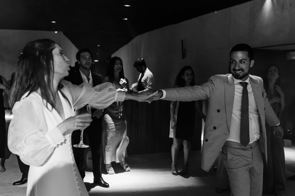 Wedding guests dance and celebrate together on the dance floor at a reception in black and white photography.