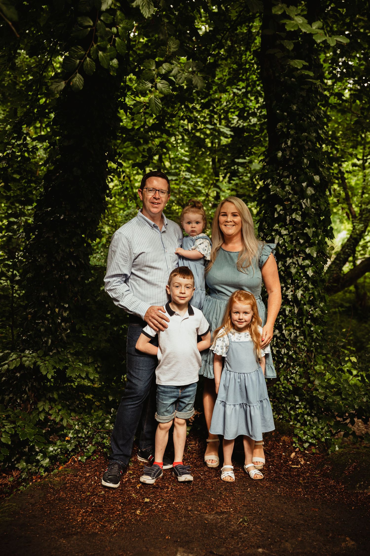 Family of 5 posing for the camera in the woods
