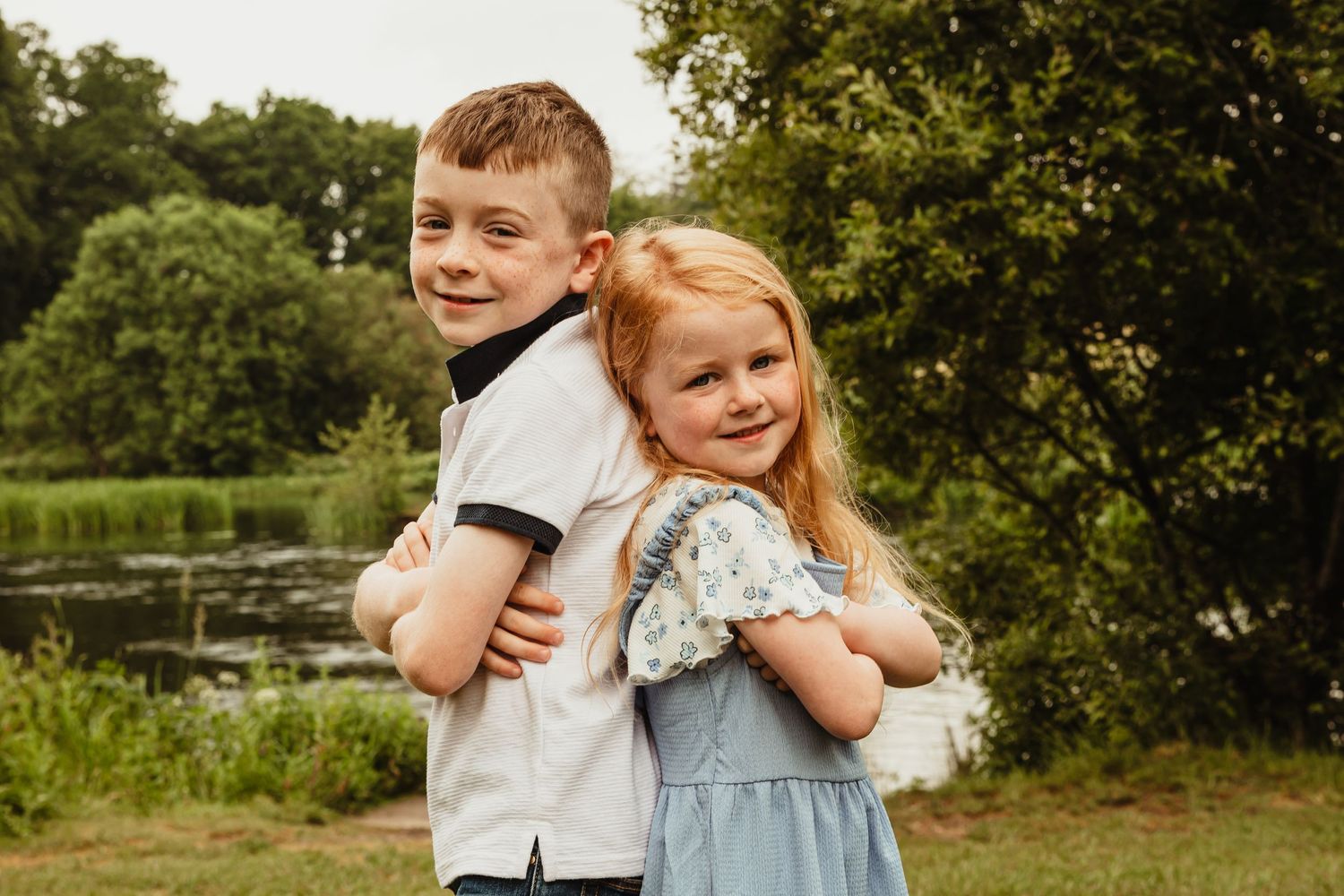 Brother and sister standing back to back smiling
