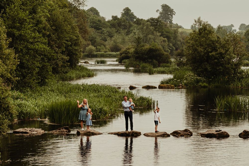 Family standing on stepping stones on a river