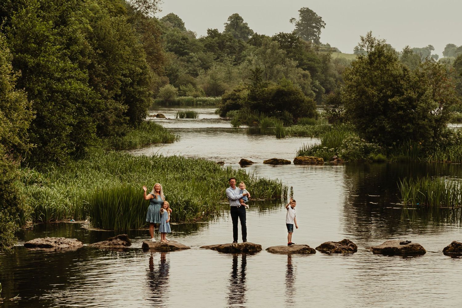 Family standing on stepping stones on a river