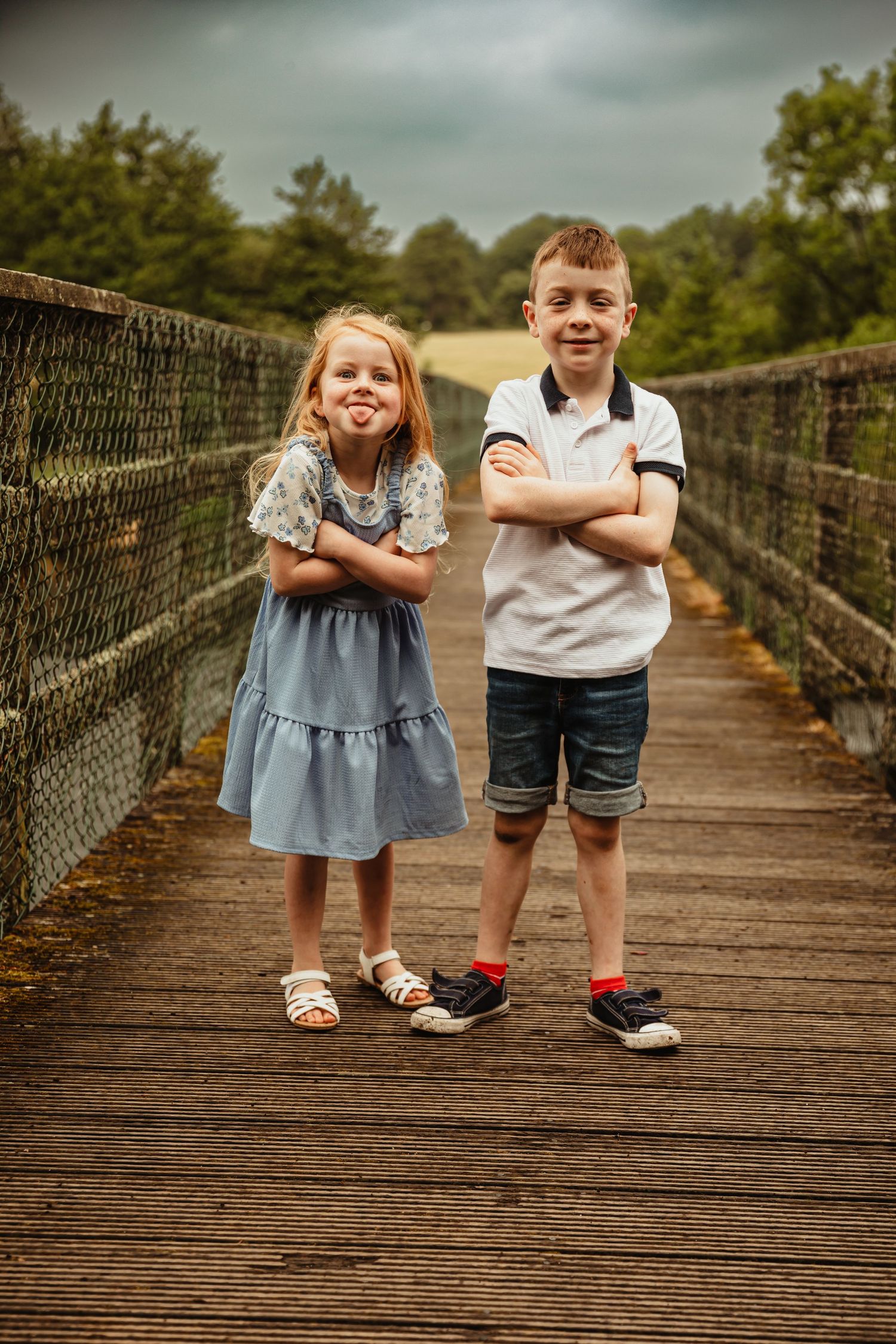 Sister and brother standing on bridge making silly faces