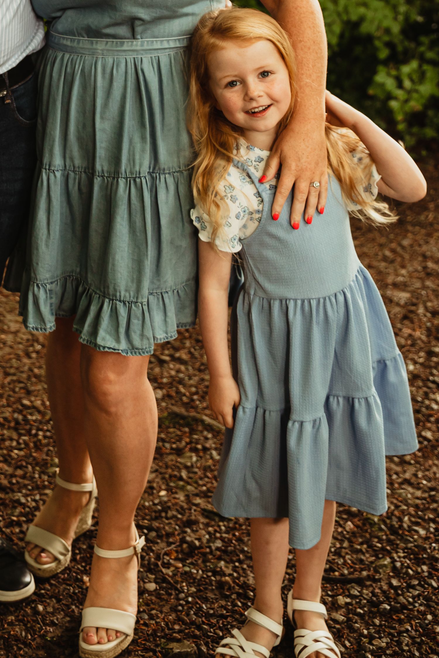 Young girl with red hair stands close to mother